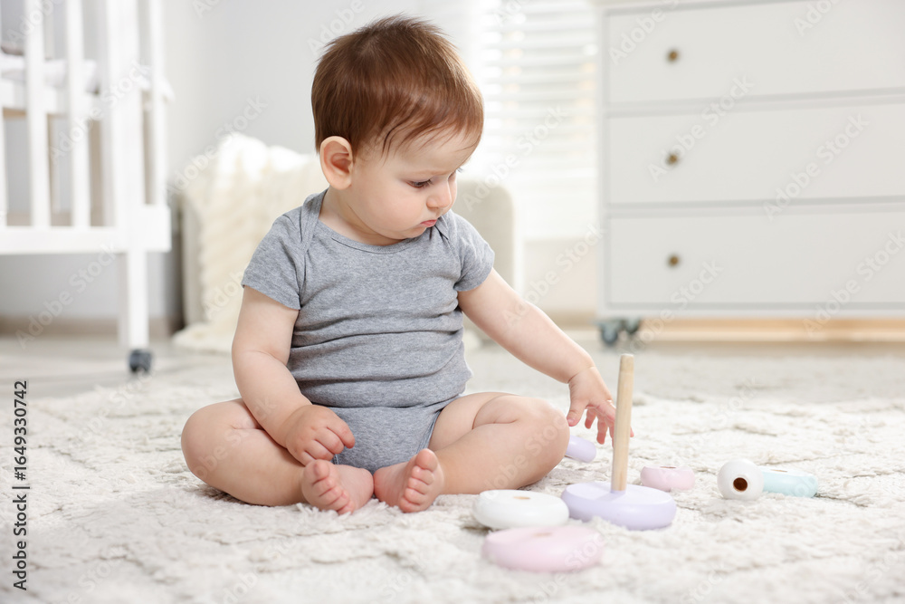 Fototapeta premium Cute little baby playing with toy pyramid in room
