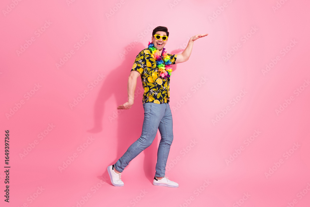 Fototapeta premium Joyful man in colorful summer outfit and sunglass posing on pink background with cheerful expression and confident gestures