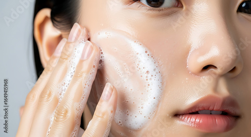 A close-up of a woman washing her face with a rich, bubbly cleansing foam for her daily skincare routine.