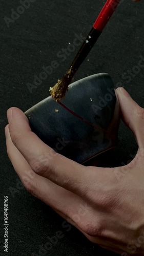 kintsugi gold cracks restoration process, Japanese black bowl fixed with the antique kintsukuroi restoration technique, the beauty of imperfections, representation of a trauma