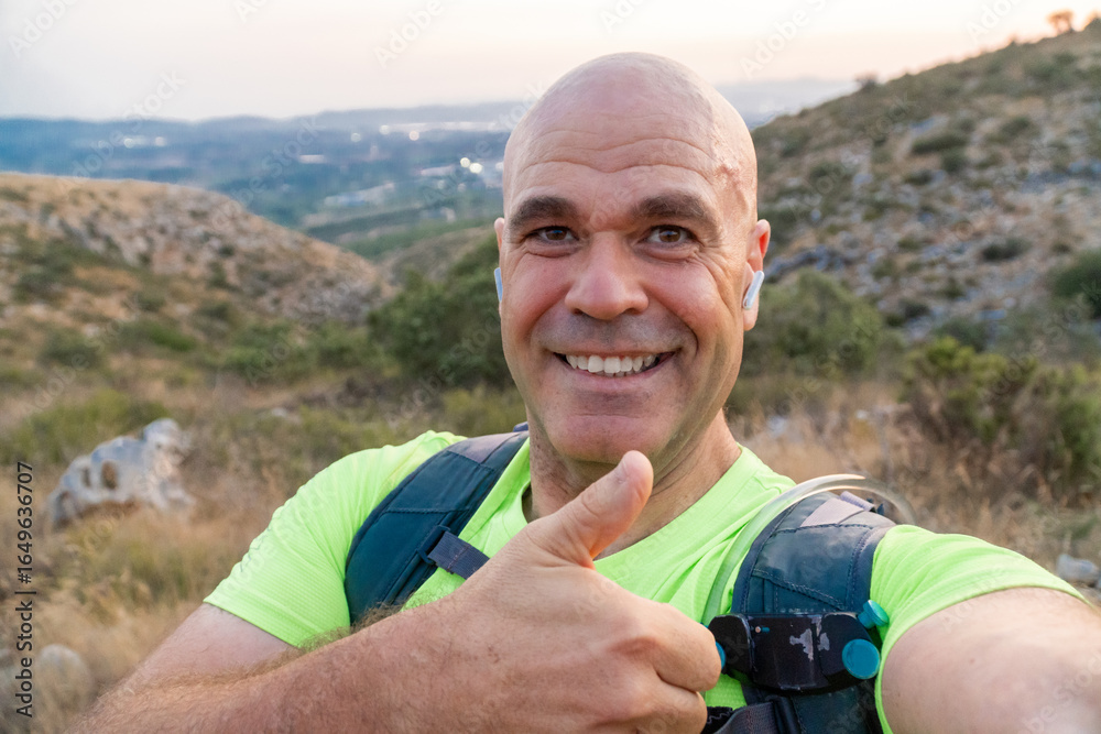 Naklejka premium Smiling hiker taking a selfie at sunset outdoors.