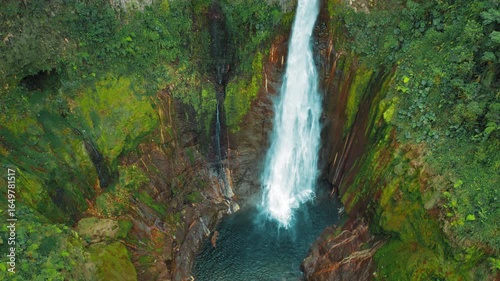 Blue Falls waterfall Catarata del Toro crashing into blue basin surrounded by jungle cliffs in Costa Rica
