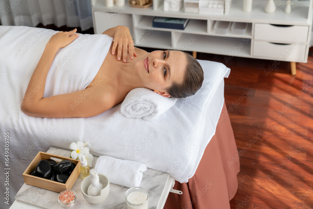 Obraz premium Caucasian woman customer enjoying relaxing anti-stress spa massage and pampering with beauty skin recreation leisure in day light ambient salon spa at luxury resort or hotel. Quiescent