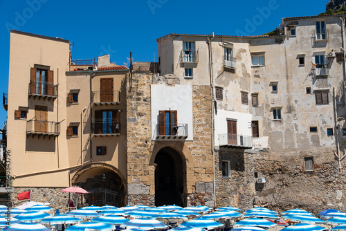 Fototapeta Naklejka Na Ścianę i Meble -  The typical houses of Cefalù seen from the sandy beach, with colorful facades, stone walls, and balconies.