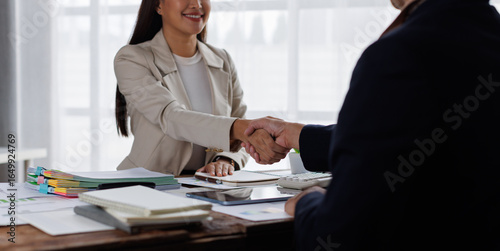 Happy financial advisor Banker and client shaking hands after business loan grant.