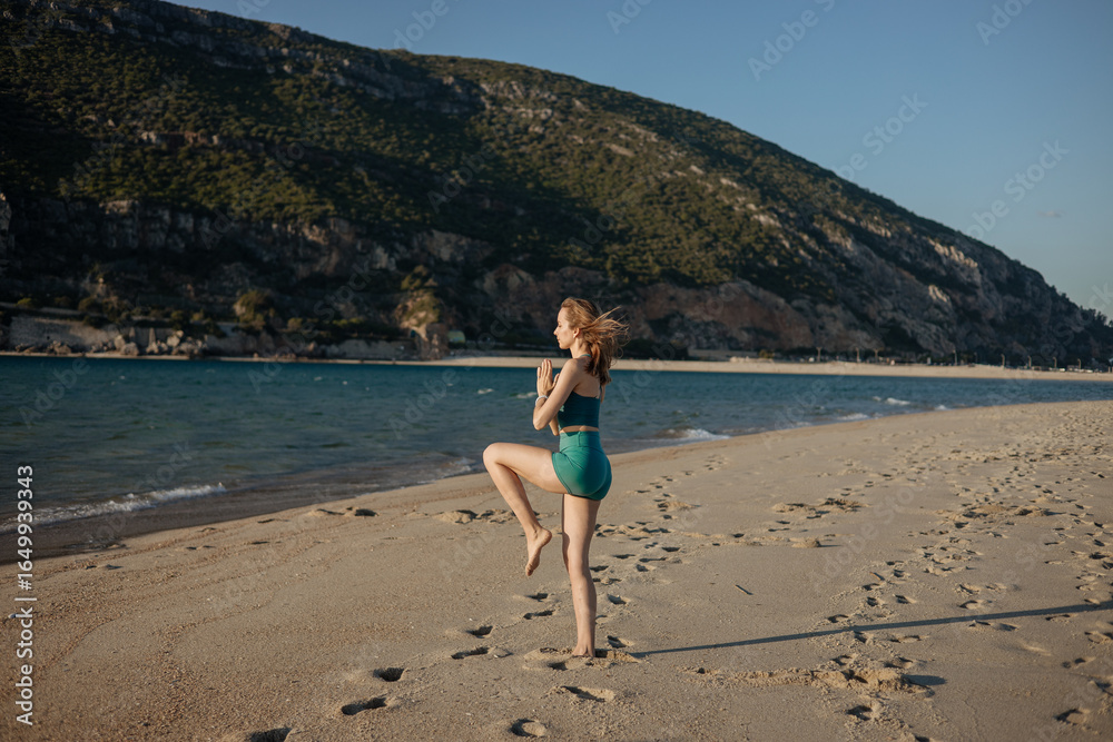 Young woman practicing yoga balance postures on the beach, stretching and standing on one leg. Outdoor fitness routine with ocean view, calm and mindful movement Young woman practicing yoga balance postures on the beach, stretching and standing on one leg. Outdoor fitness routine with ocean view, calm and mindful movement