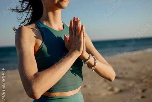 Fotografie Close-up portraits of a young woman meditating on the beach with hands in prayer position