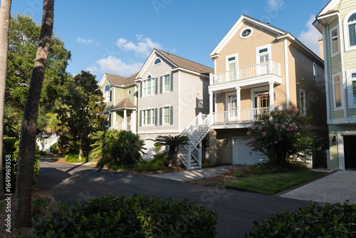 Isle of Palms, South Carolina, USA - June 30, 2025: A row of pastel-colored coastal homes with balconies and palm trees along a quiet residential street under a sunny blue sky.