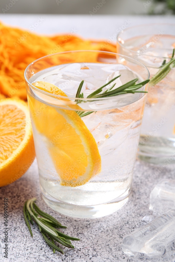 Fototapeta premium Sparkling water with orange slices and rosemary on grey table, closeup