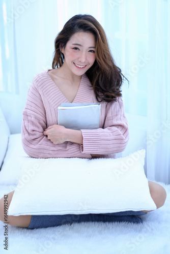 Free Download Beautiful Smiling Young Asian Woman with Clean, Fresh, Glow, and pefect Skin in pink sweater, winter concept. Happy, healthy, cheerful, relaxing girl in white living room. - GFXLoad