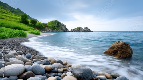 Beautiful coastal scenery with smooth pebbles and calm waters under a blue sky.