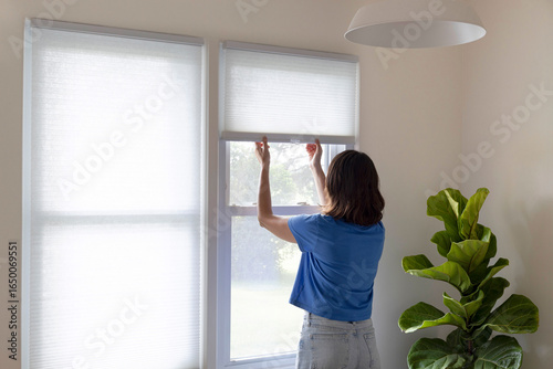 Tableau sur toile Woman closing window shades