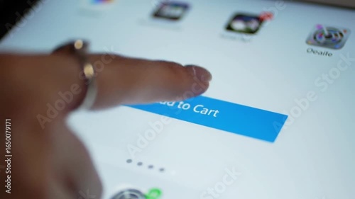 Close-up of a finger tapping the 'Add to Cart' button on a tablet, illustrating the ease of online shopping and e-commerce.