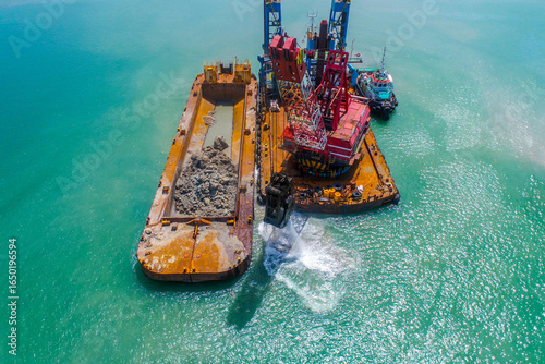 Fotografia Marine crane barge in operation, dredging rocks and dumping into cargo barge for
