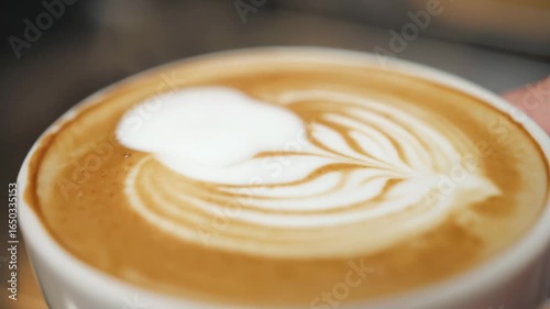 Close-up latte art in coffee cup, warm tones, barista craftsmanship