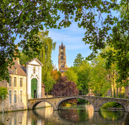 The bridge leading to the historic Beguinage of the city of Bruges (Brugge), Belgium, with the bell tower of St. Saviour's cathedral in the background,