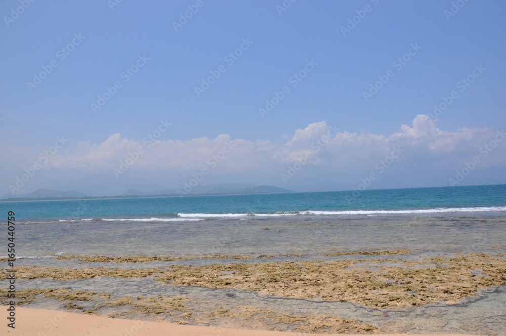 Obraz premium Sea background, beach and sand, sunny day, rock from waters, clear sky
