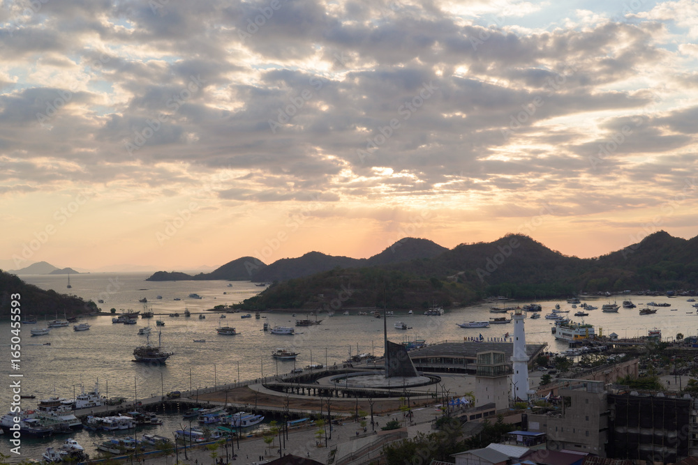 Fototapeta premium Scenery of Labuan Bajo harbor with boat sailing in the ocean and the cityscape, Indonesia tourist destination.