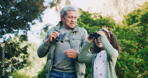 Grandfather, girl and binocular in park for travel, sightseeing or search with view for bonding. Old man, child and explore for adventure, bird watching or together in nature with family in Mexico