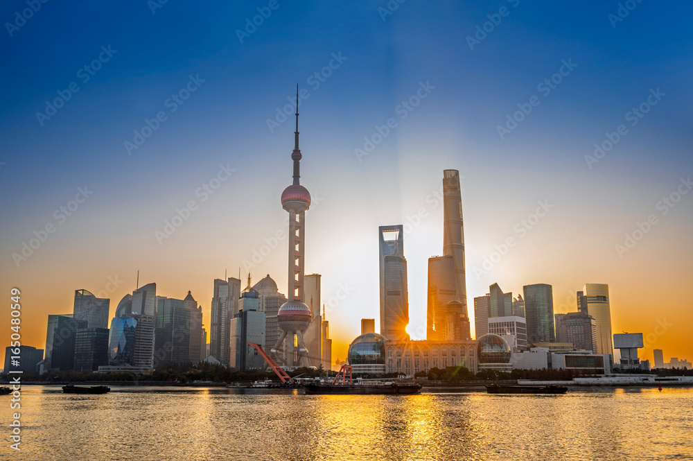 Fototapeta premium Sun rise of Shanghai city modern skyscraper cityscape in blue sky autumn season behind pollution haze, view from the bund in Shanghai, China.