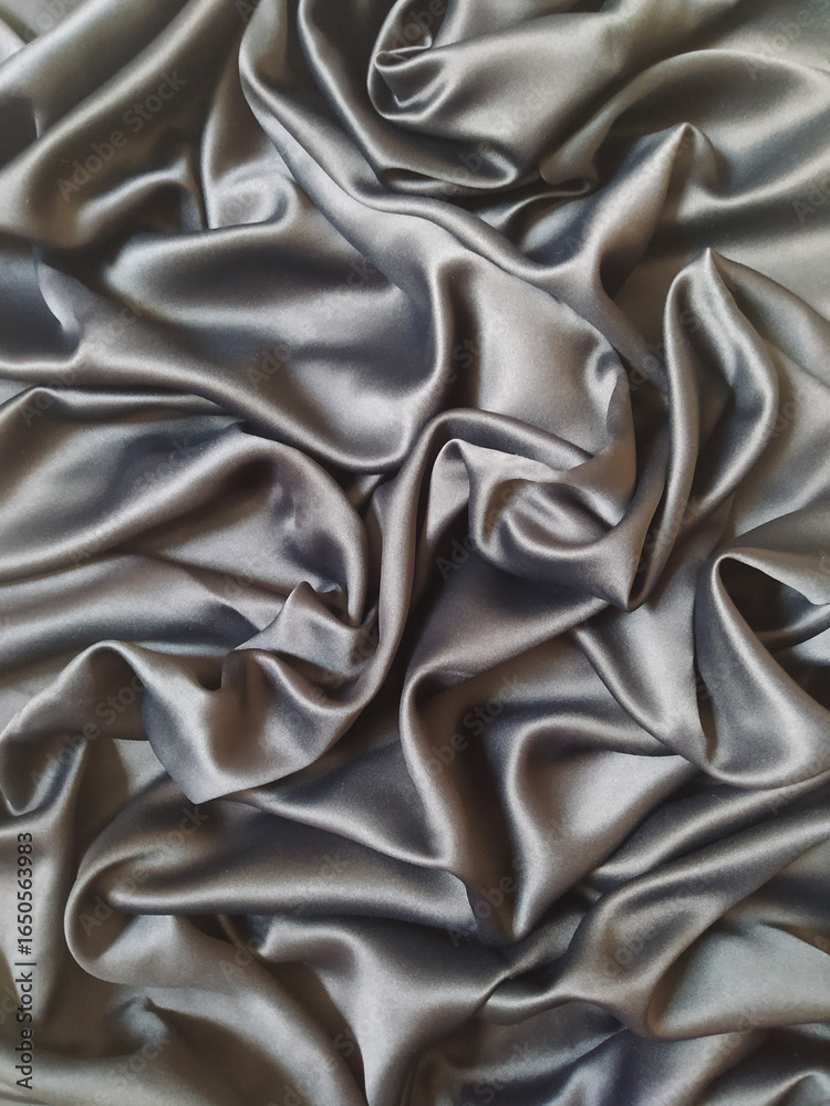 Fototapeta premium Luxurious silver silk fabric with elegant folds and flowing drapes texture background