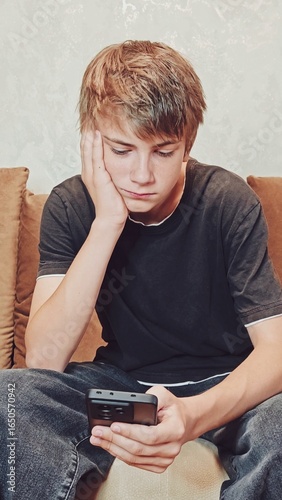 Boy using smartphone. young Caucasian guy in a melancholic mood scrolls through social media and doesn't know what to do next.