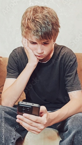 Handsome melancholic Teenager uses a phone. Technology and People Concept. Man Watching Video, Scrolling Through Social Networks. Technology and People Concept