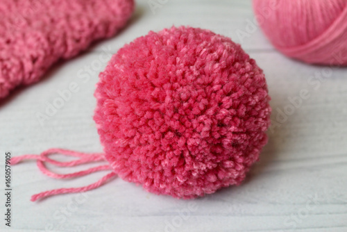 Beautiful, large, fluffy pink pompom made by hand from soft yarn for decorating a hat, on a light background. Handmade.