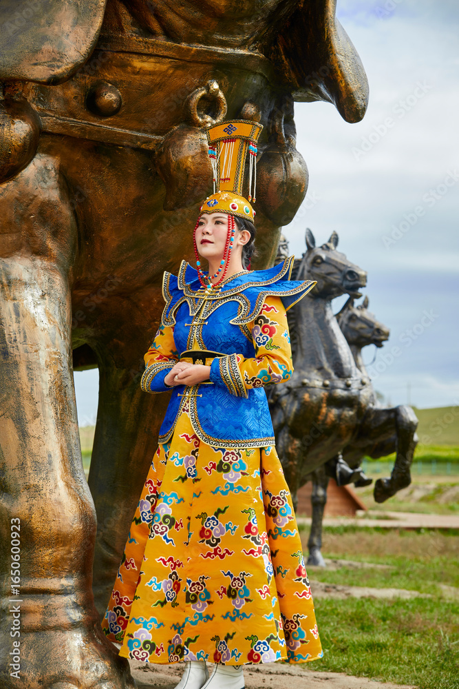 Fototapeta premium Mongolian girls dressed in luxurious Mongolian costumes on the Mongolian war chariots of the Jinyuan Grand Tent on the grassland