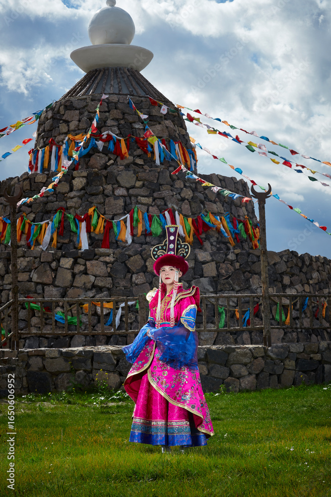 Naklejka premium Mongolian girls dressed in luxurious Mongolian costumes in front of an obo on the grassland