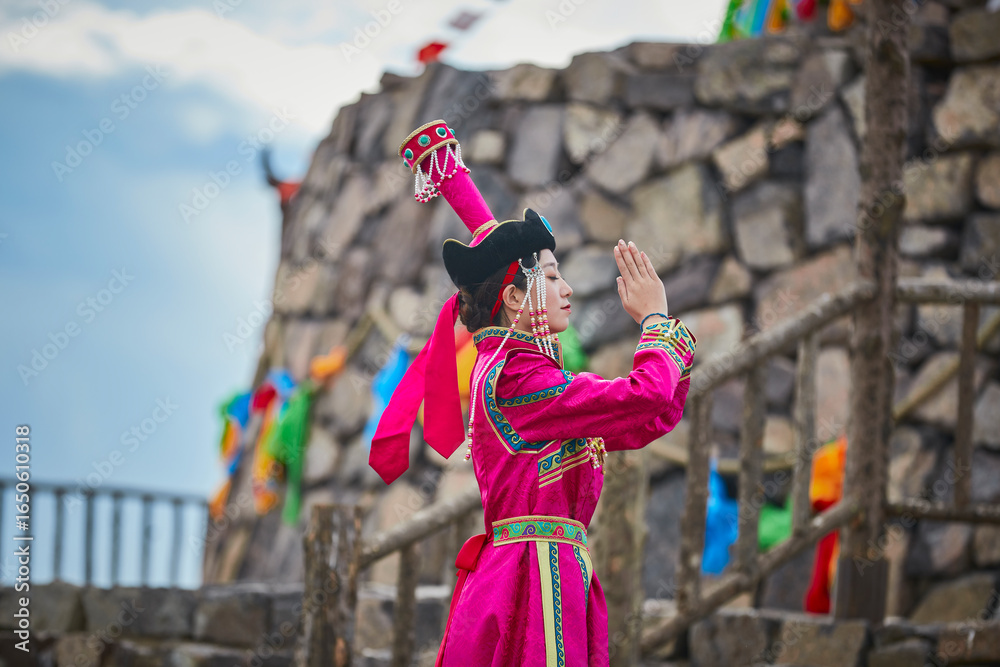 Fototapeta premium Mongolian girls dressed in luxurious Mongolian costumes in front of an obo on the grassland