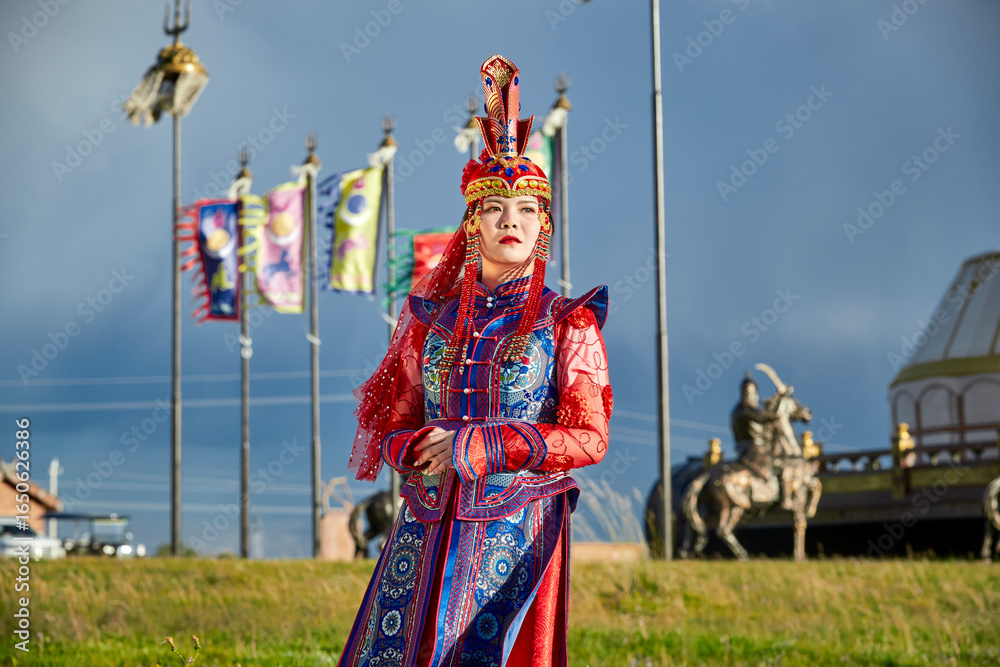 Naklejka premium Mongolian girls dressed in luxurious Mongolian costumes in front of a yurt on the grassland