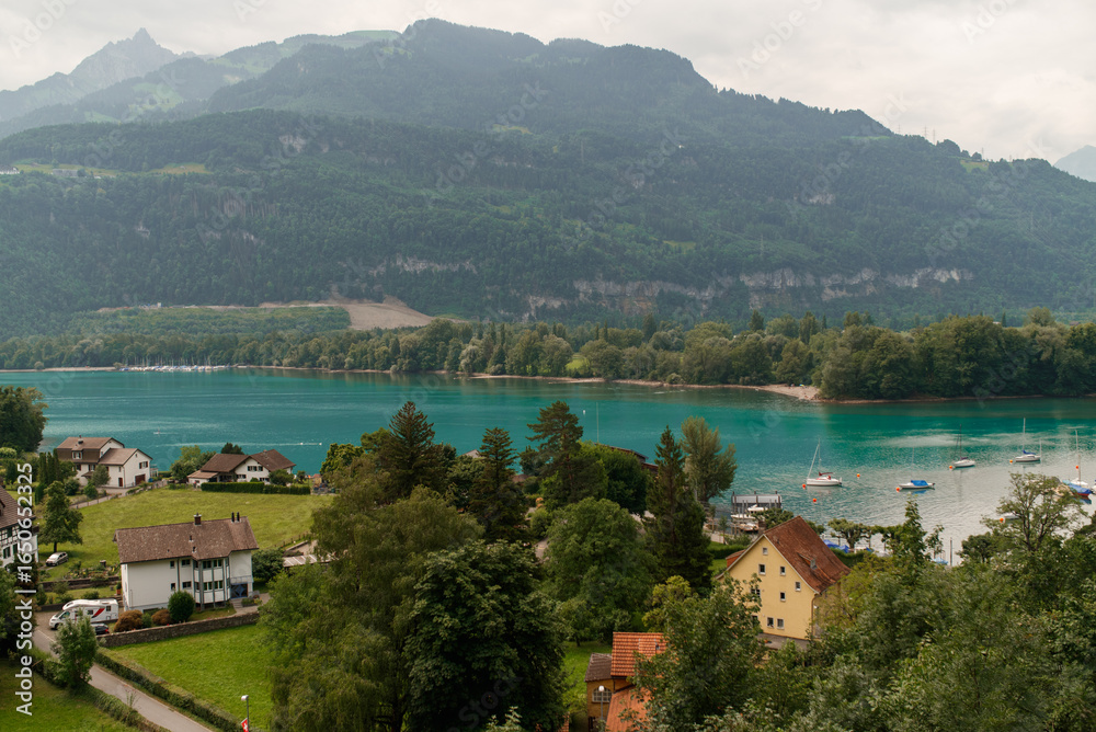 Fototapeta premium View of Lake Walen, Switzerland, Swiss Alps, Canton St. Gallen, Chatzenberg, summer 2025. Trees, meadows and small villages in the valley. mountains, beautiful landscape hiking, recreation.