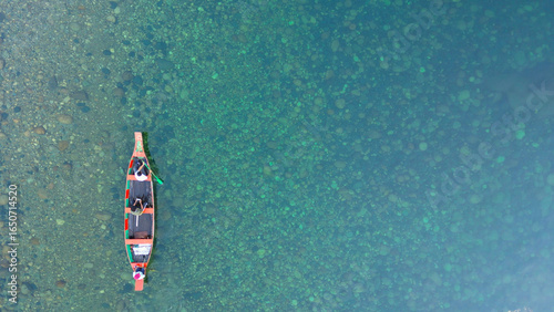 Tableau sur toile op aerial drone view of three people sitting in a wooden boat on the crystal-clear Dawki River in Meghalaya, India