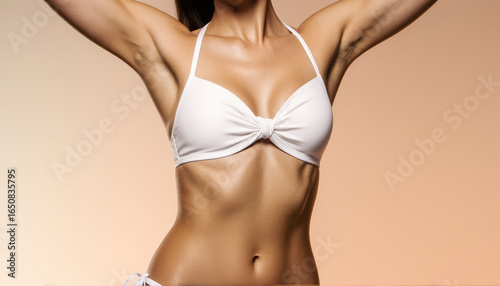 A premium studio photo of a sun kissed woman's torso. The pose with lifted arms accentuates her waist and curves, creating an elegant visual.