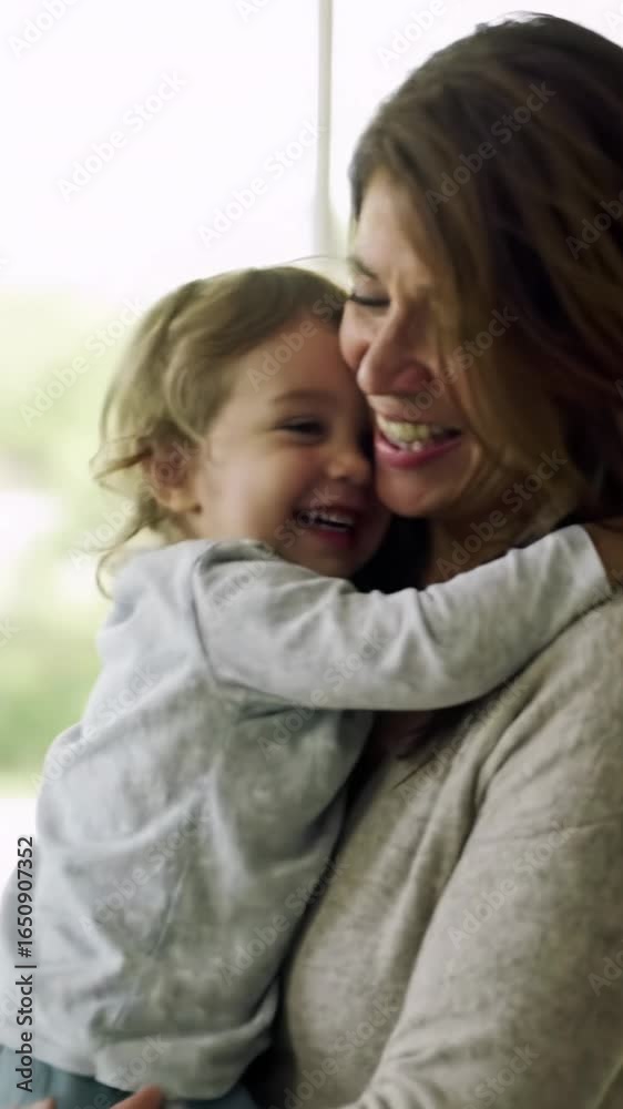 Adult with gentle hands lifts giggling child in sun-dappled interior. Both share radiant smiles, deep affection & profound security in a medium close-up video with creamy bokeh. Concept of Adult with gentle hands lifts giggling child in sun-dappled interior. Both share radiant smiles, deep affection & profound security in a medium close-up video with creamy bokeh. Concept of