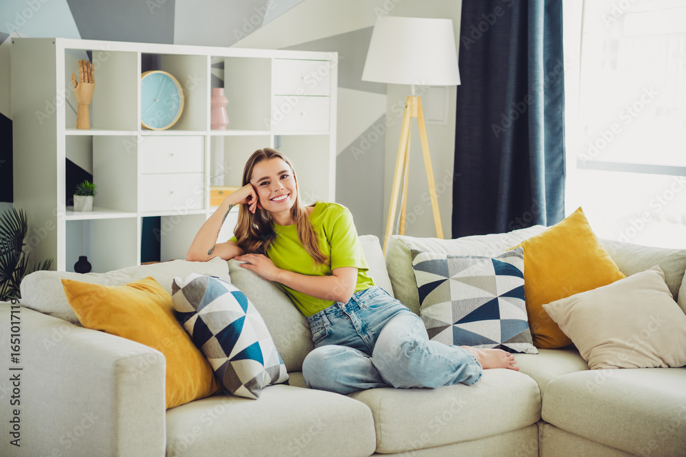 Obraz premium PrettyYoung woman relaxing on a cozy couch in a stylishly decorated living room