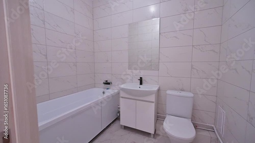 clean bathroom featuring a white tub, toilet, and sink cabinet against tiled walls