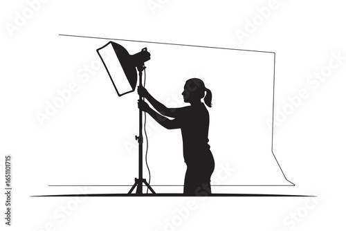 Silhouette of person adjusting studio lighting equipment