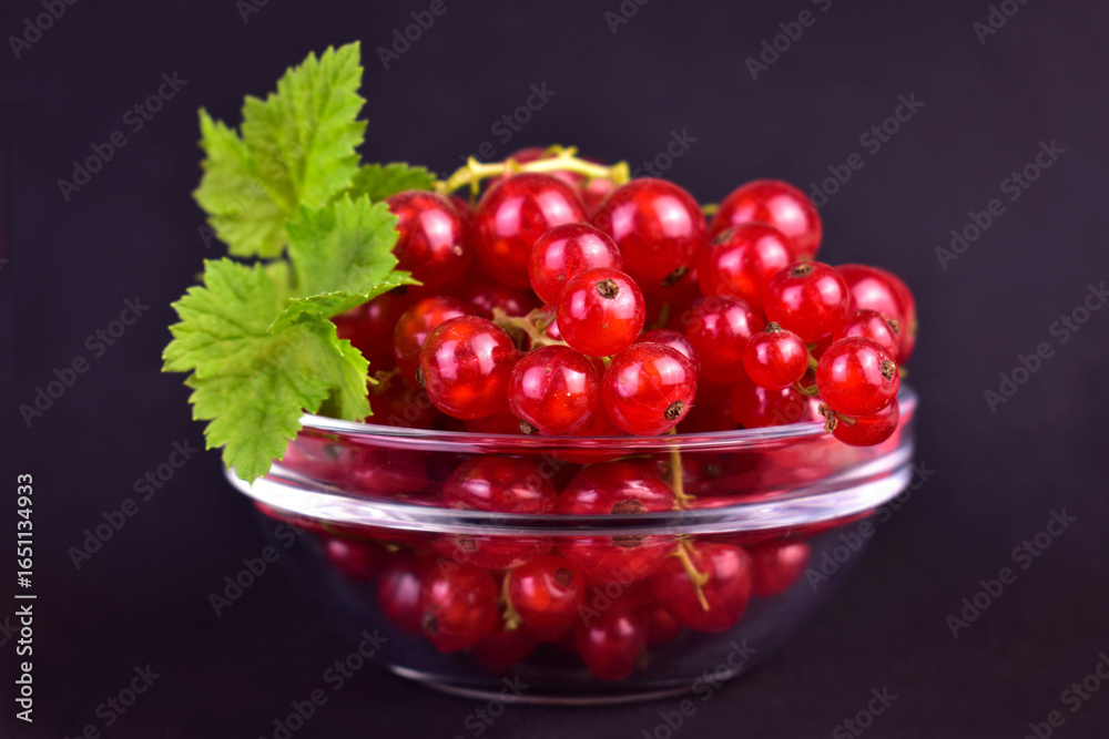 Red currant berries in a glass bowl on a black background. Close-up.
Red currant berries in a glass bowl on a black background. Close-up.