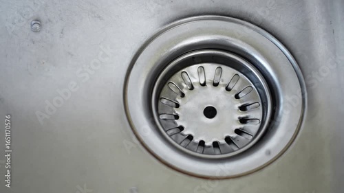 Water drain down on stainless steel kitchen sink hole, cleaning and hygiene concept.