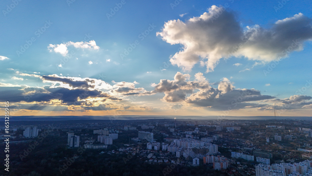 Fototapeta premium Scenic aerial view of cityscape with dramatic sunset sky and clouds