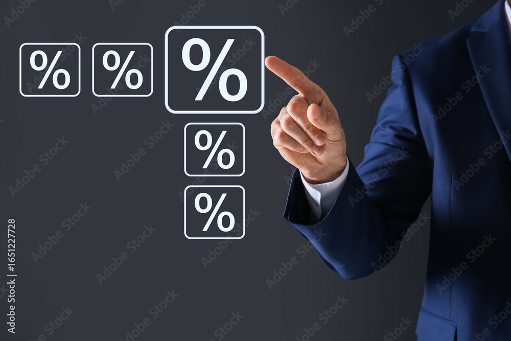 Obraz premium Businessman touching percent sign on virtual screen against dark grey background, closeup