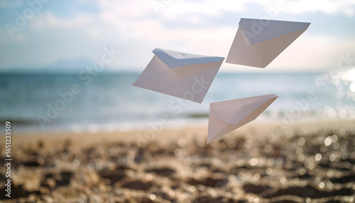 Three White Paper Envelopes Floating Above Sandy Beach And Sparkling Sea Under Bright Sunlight