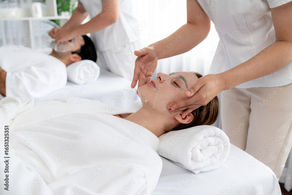 Obraz premium Serene modern daylight ambiance of spa salon, couple customer indulges in rejuvenating with facial skincare mask. Facial skin treatment and beauty cosmetology procedure for face. Quiescent