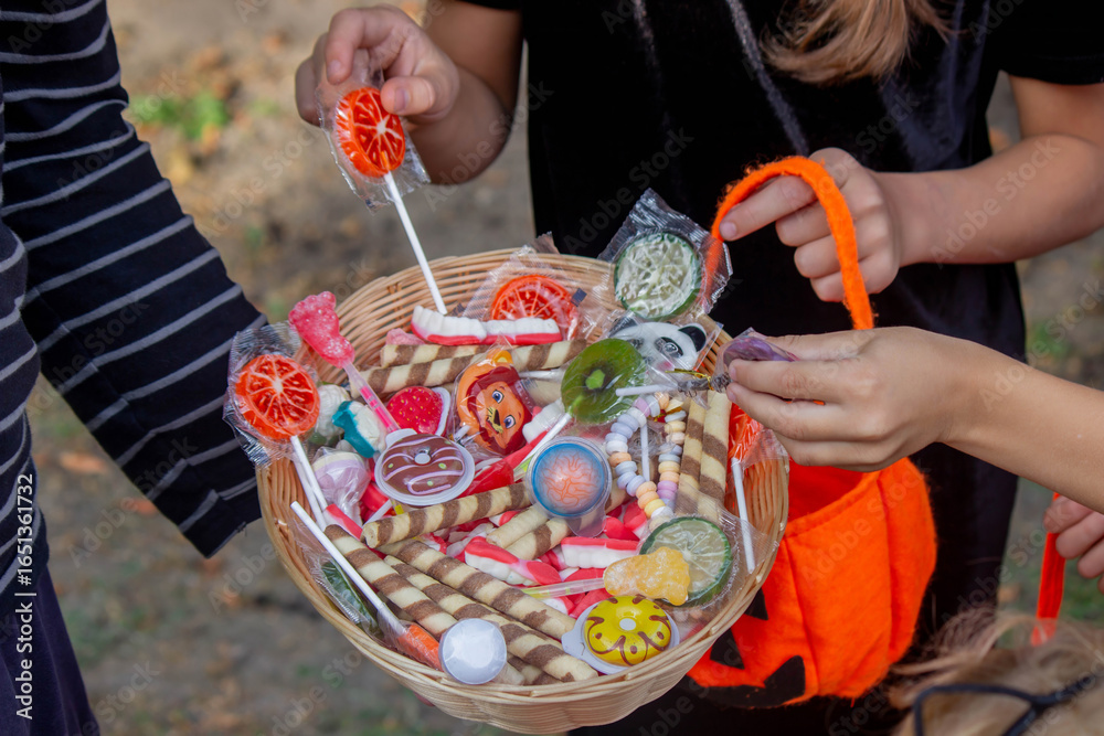 Fototapeta premium Children collecting candy for Halloween. Selective focus