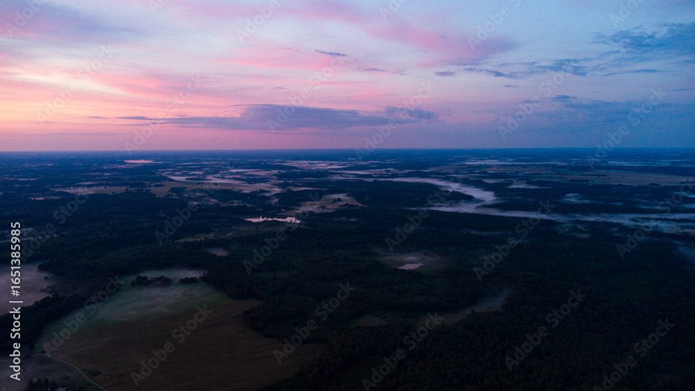 Fototapeta premium Aerial View of Serene Misty Landscape at Dawn with Vibrant Sunrise