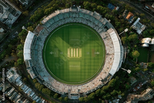 Aerial view of a packed cricket stadium / Top view of international cricket arena with bright green pitch / Drone shot of green cricket field