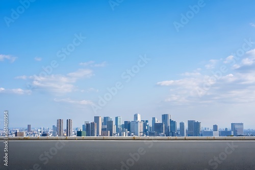 Modern city skyline under a bright blue sky with light clouds and a flat paved foreground