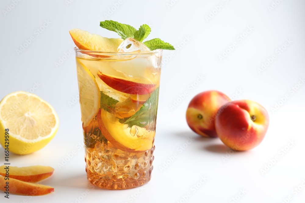 Fototapeta premium Tasty iced tea with lemon, peaches and mint on white background